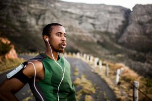 Runner breathing heavily while taking a break from his morning exercise with his earphones in