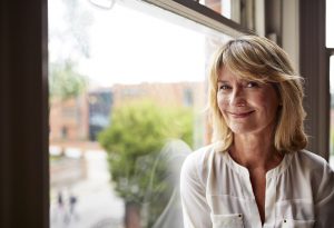 Portrait of a smiling mature woman sitting by a window at home